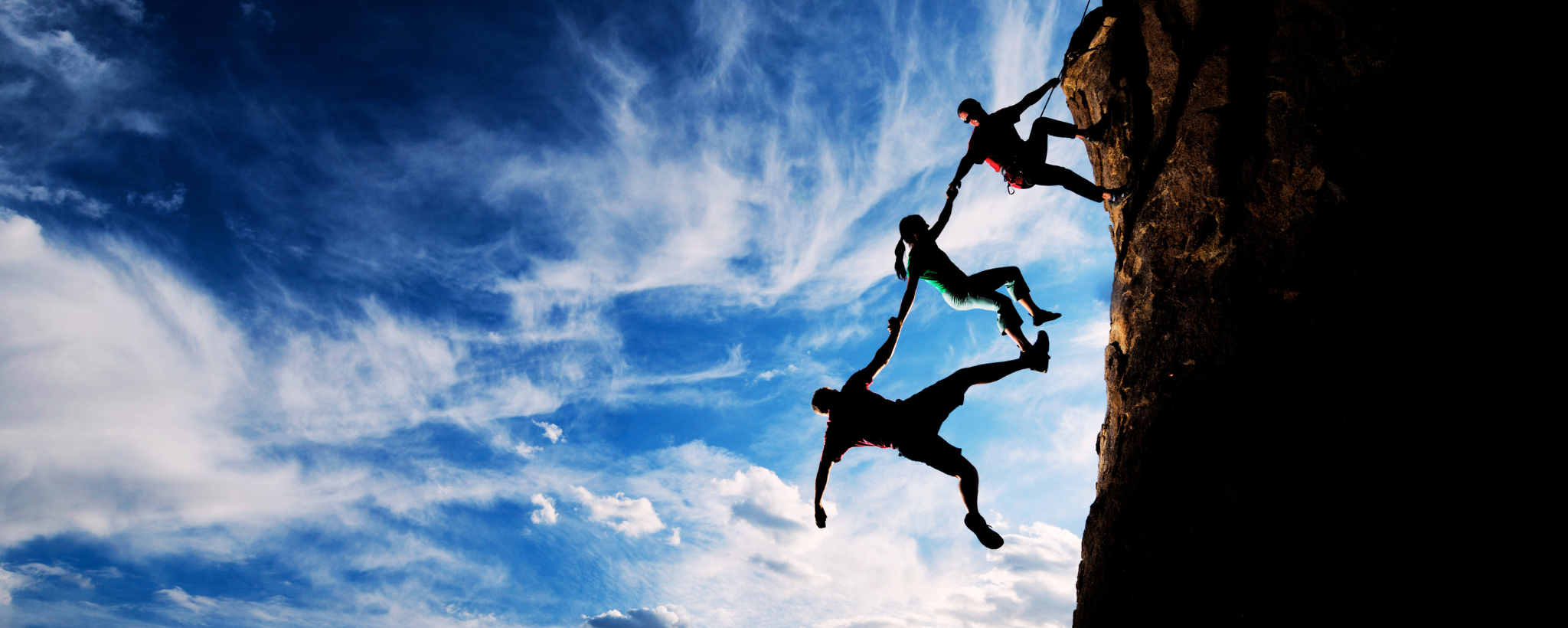 3 people climbing a mountain trusting each other to hold on